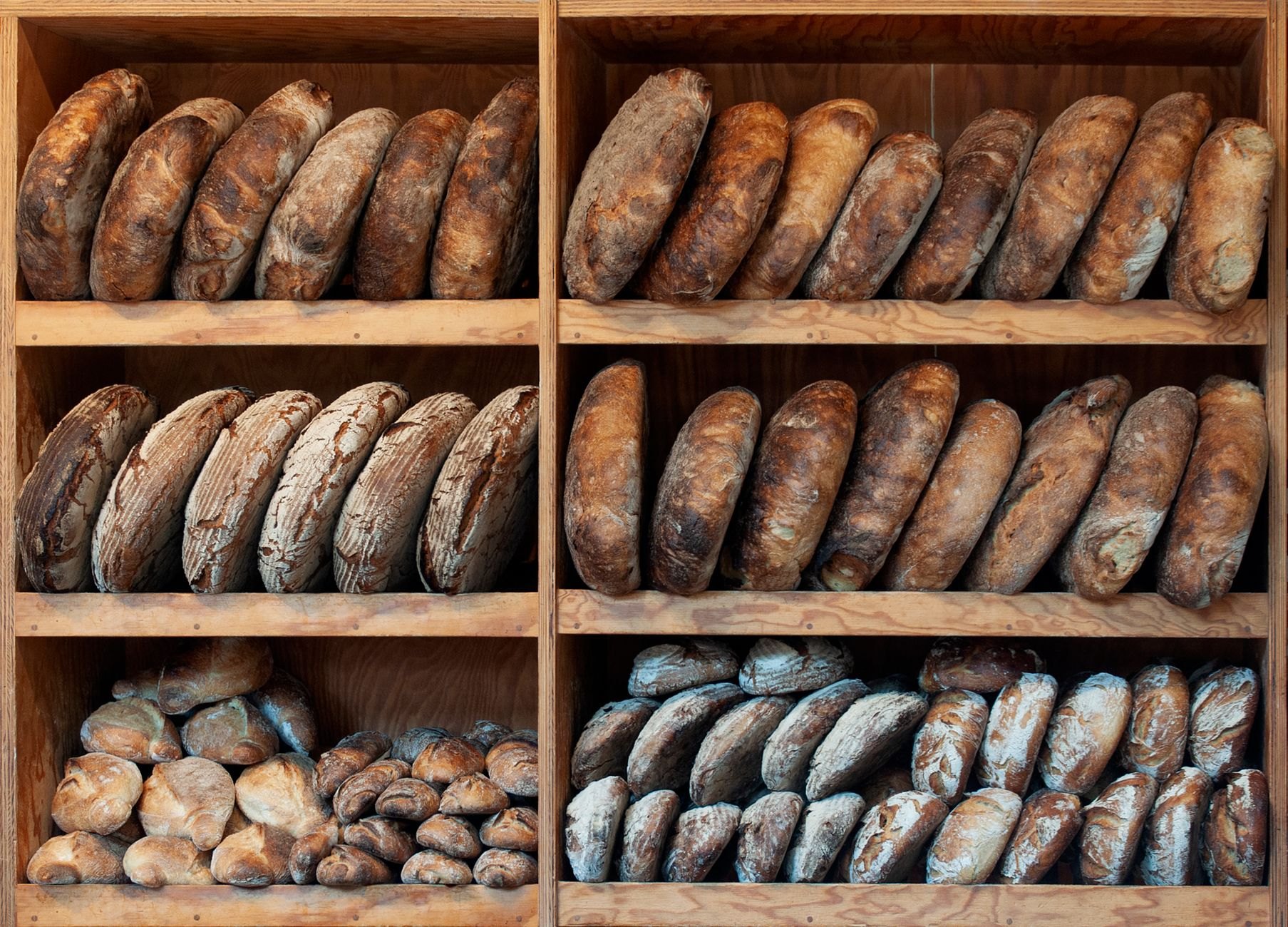 Freshly baked artisan bread loaves on wooden bakery display shelves