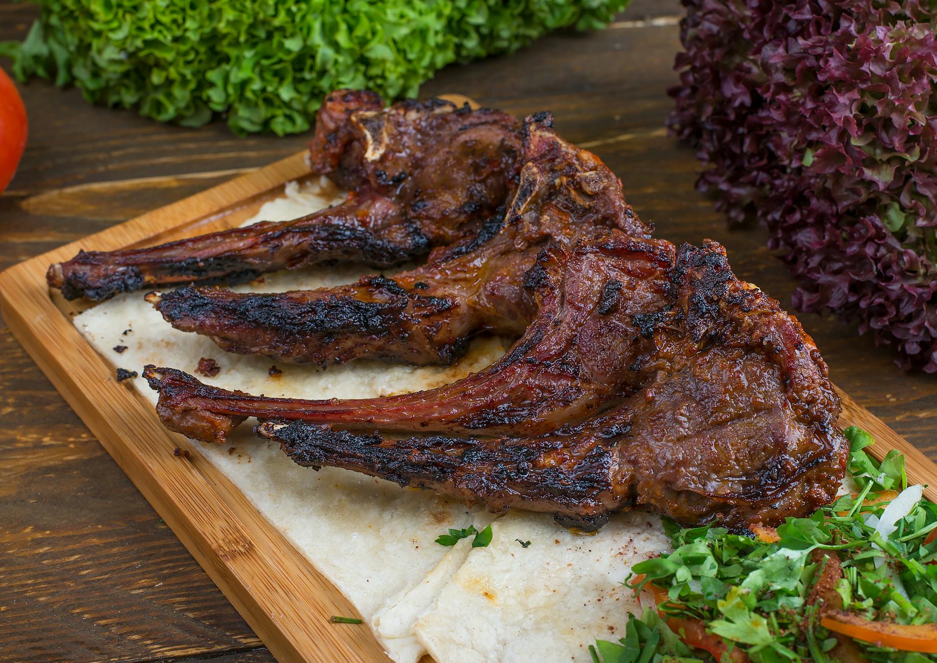 Freshly grilled and marinated lamb chops on display at deli counter