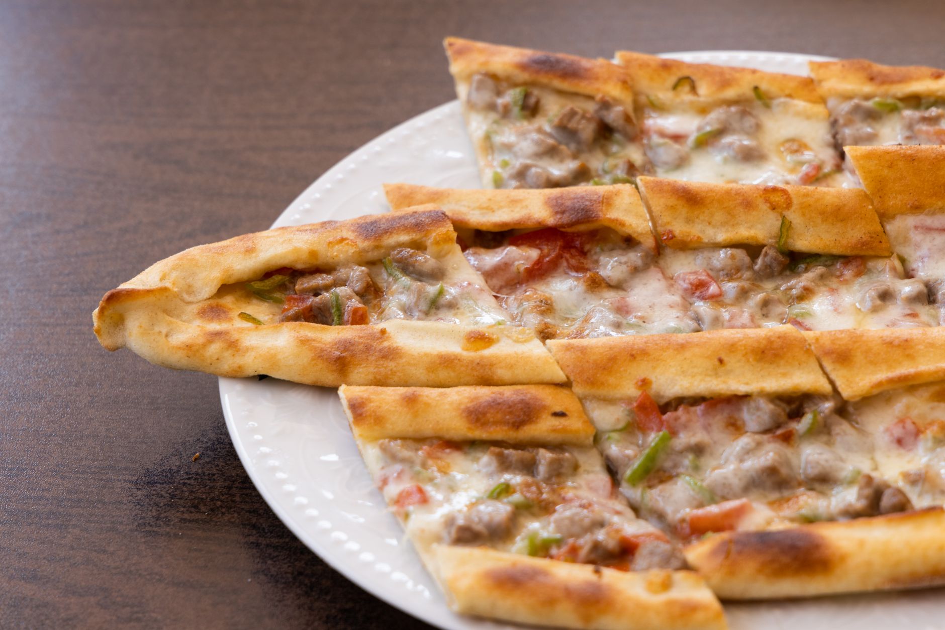 Turkish pide fresh from oven on rustic ceramic plate with fresh tomato salad