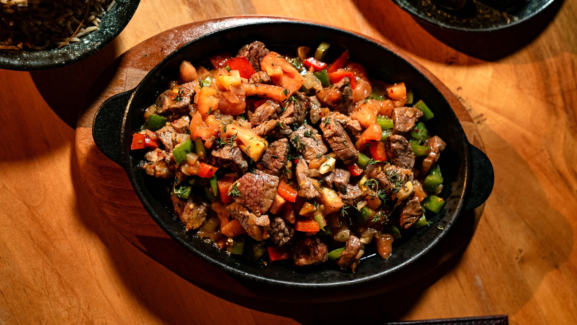 Slow-braised lamb shank in rich sauce served in a clay pot with vegetables