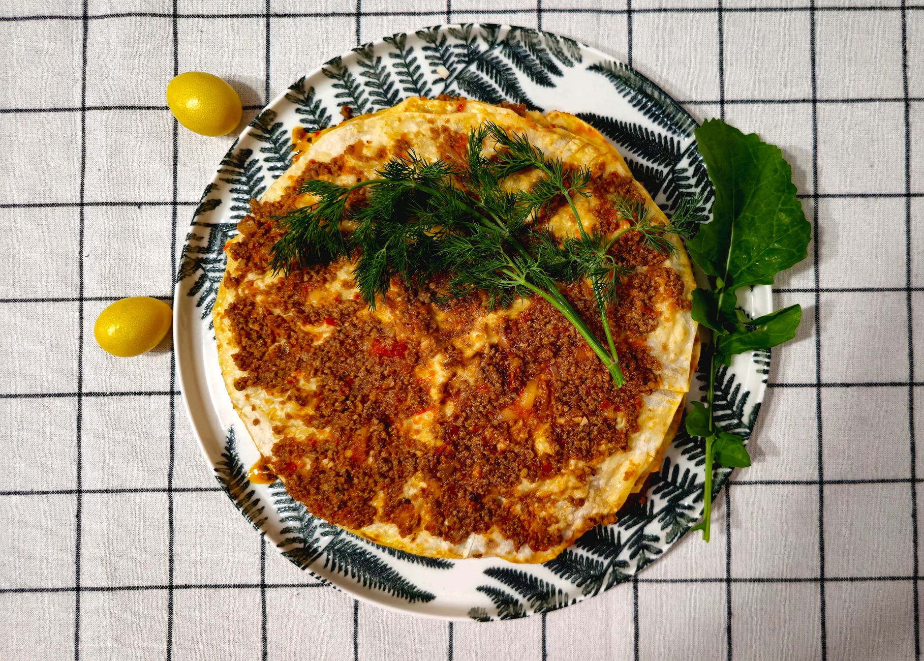Freshly baked lahmacun rolled with parsley and lemon on a wooden board