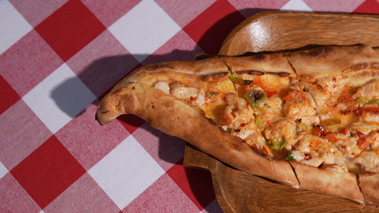 Freshly baked lahmacun on a wooden board with lemon and parsley garnish