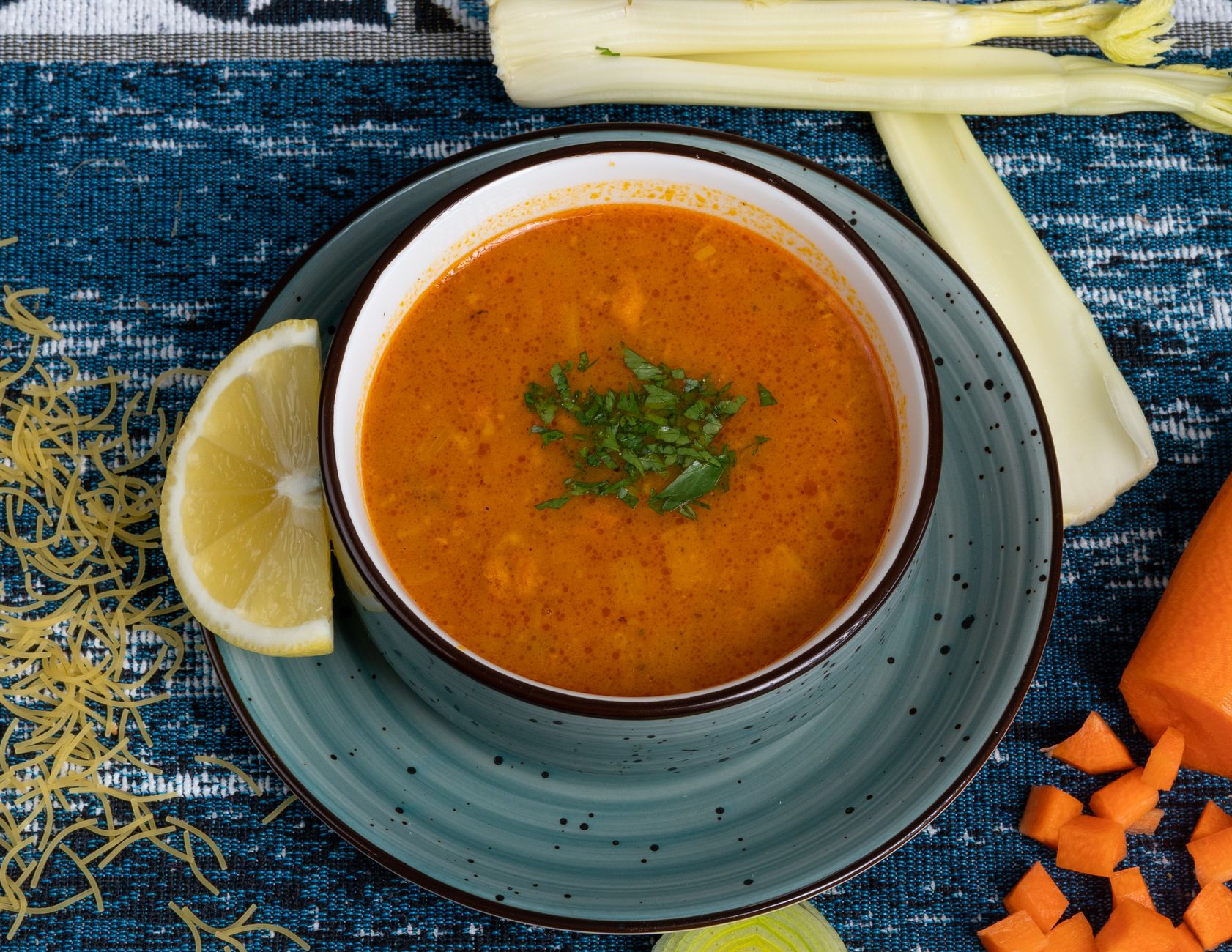 Bowl of red lentil soup with paprika butter garnish and crisp bread on the side